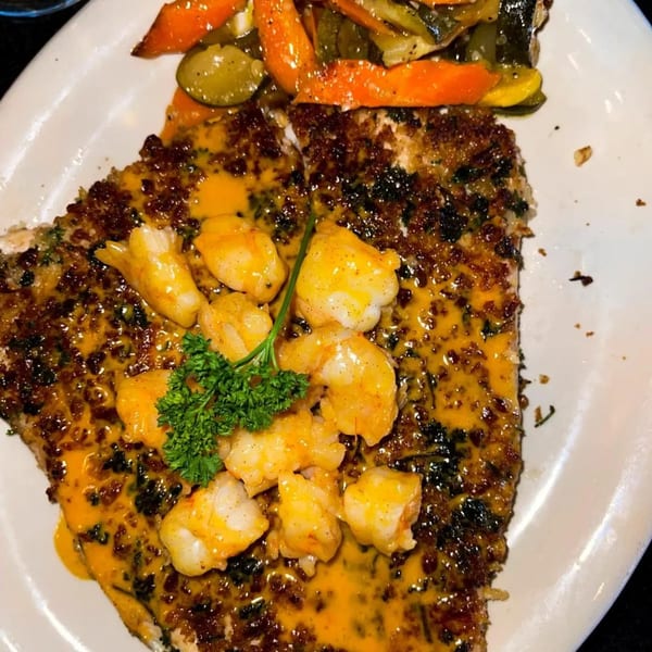Seafood dish with breaded fish, shrimp in sauce, and a side of mixed vegetables.