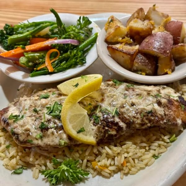 Seafood dish with grilled fish, rice, lemon, roasted potatoes, and steamed vegetables.
