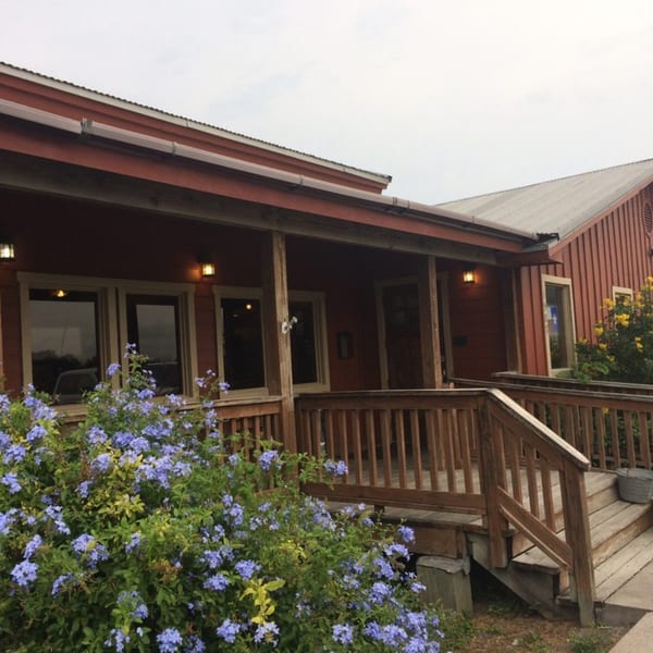 The Original Railroad Seafood Station's exterior, a rustic red building with a wooden porch and blue flowers.