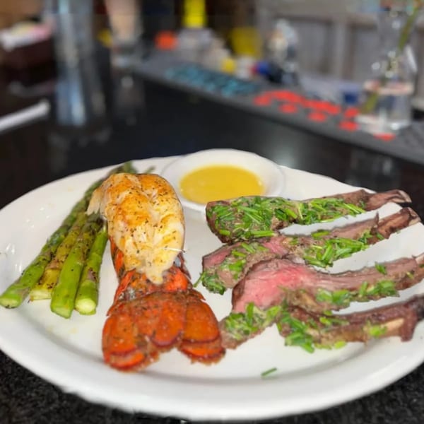 Grilled lobster tail, asparagus, and sliced steak with chives and a side of butter.